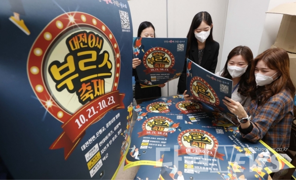 동구청 직원들이 ‘대전 0시 부르스 축제 포스터를 확인하고 있다. [사진/동구청 제공]
